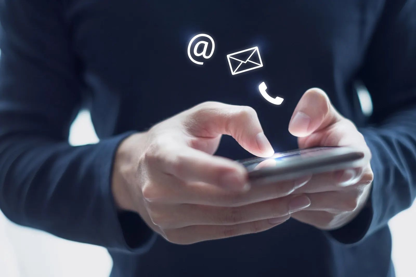 Hände tippen auf einem Smartphone, darüber Symbole für Kontakt