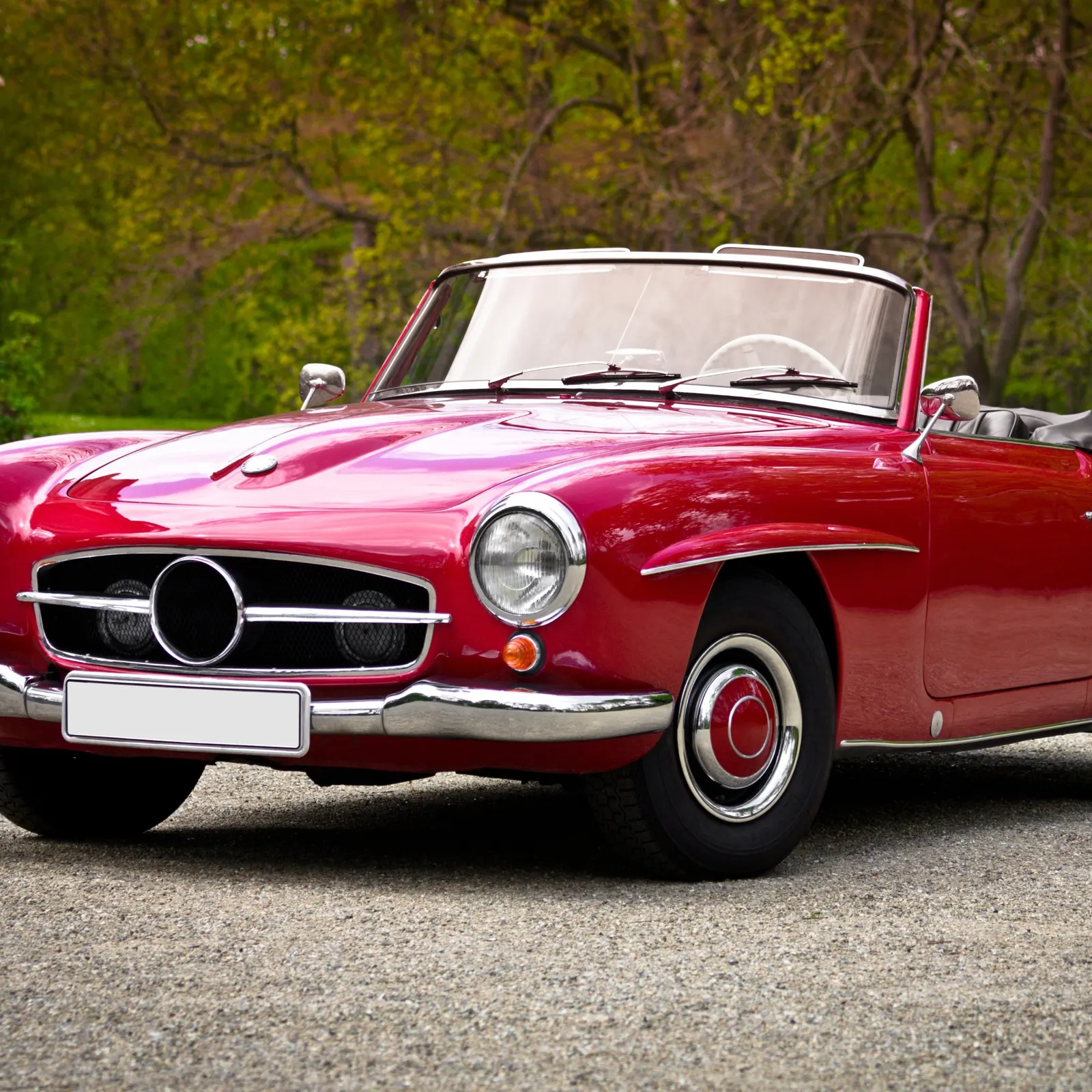 Roter Oldtimer-Roadster auf einem Kiesweg